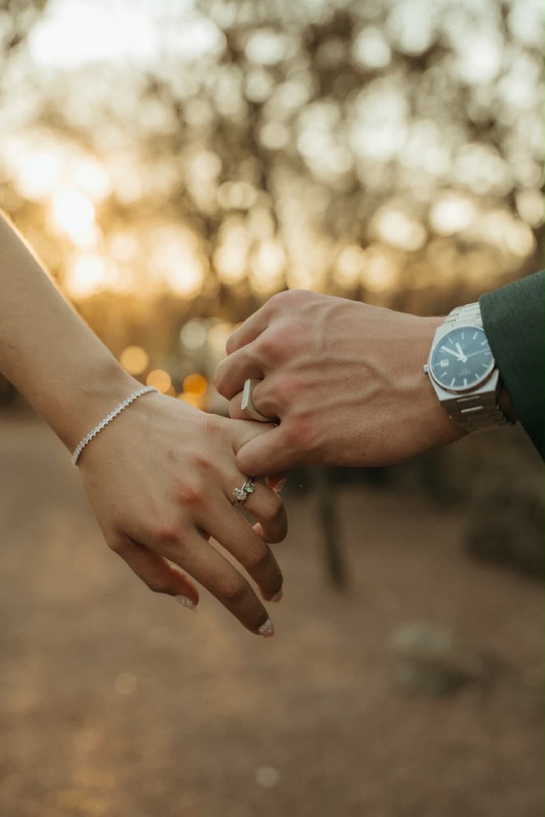 Golden hour detail of a couple holding hands, wedding rings catching the light